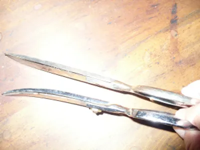 A pair of scissors sitting on top of a wooden table.