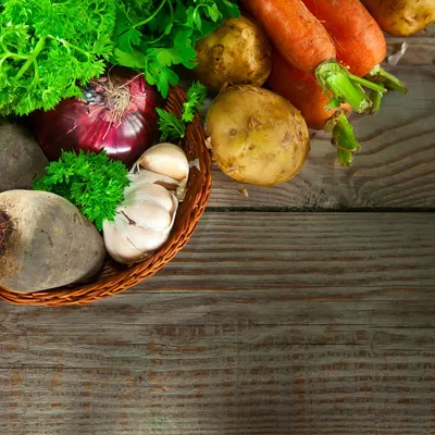 A basket of vegetables on top of a wooden table.