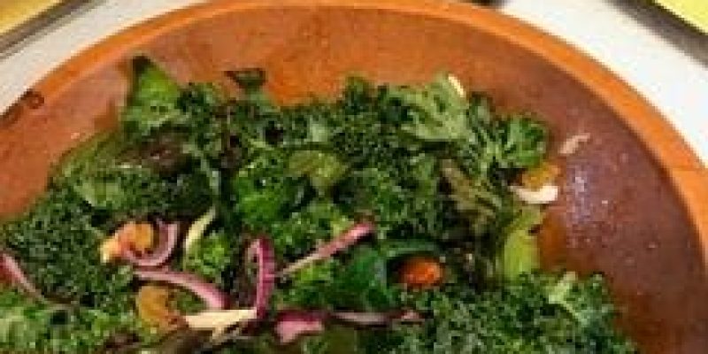 A wooden bowl of salad on top of a table.